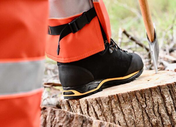 SwedePro-Chainsaw-Protector-Boot-shown stepping on tree stump