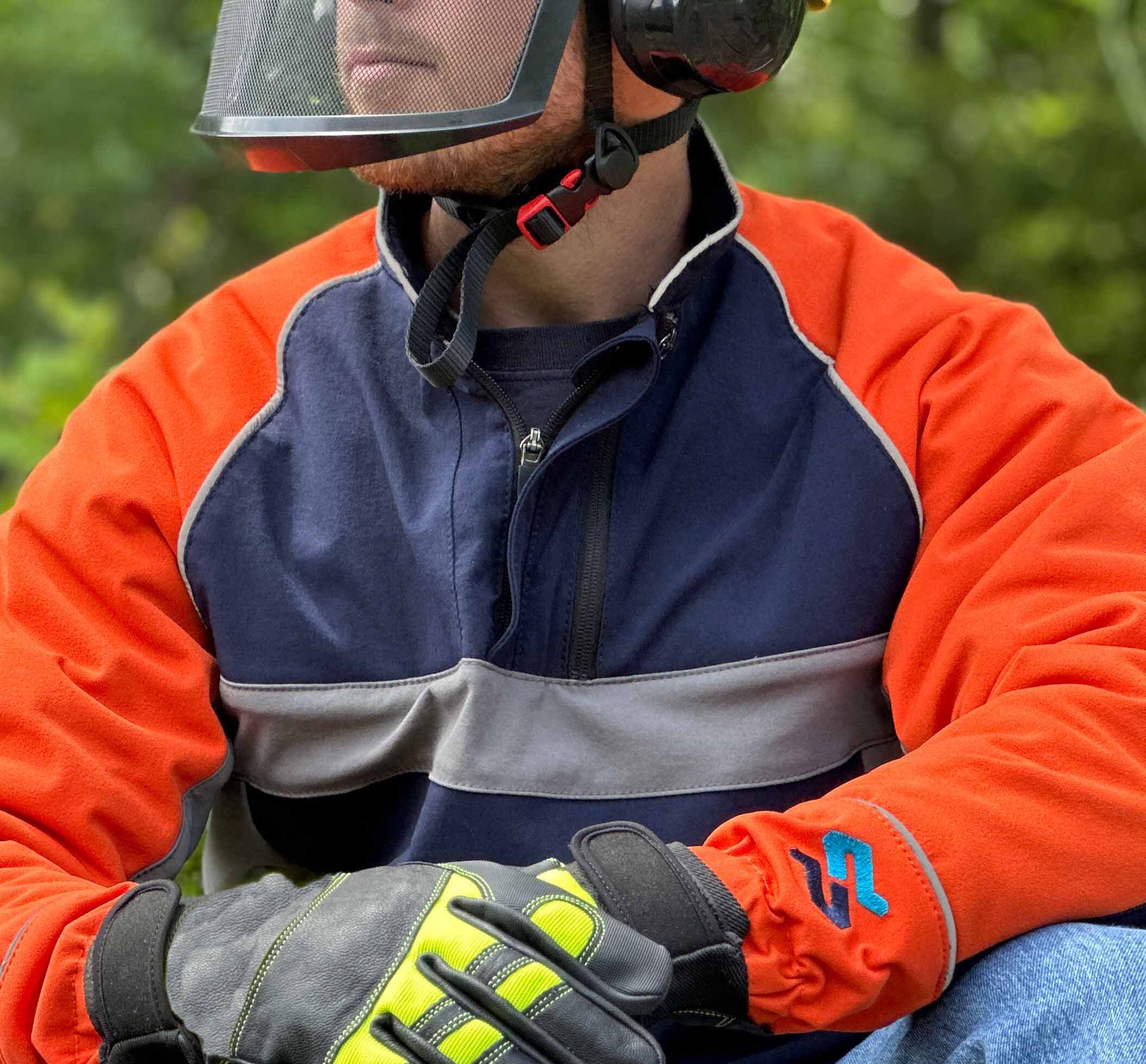 Close up of man man's left arm and hand holding a chainsaw, wearing the SwedePro professional pullover in navy with grey